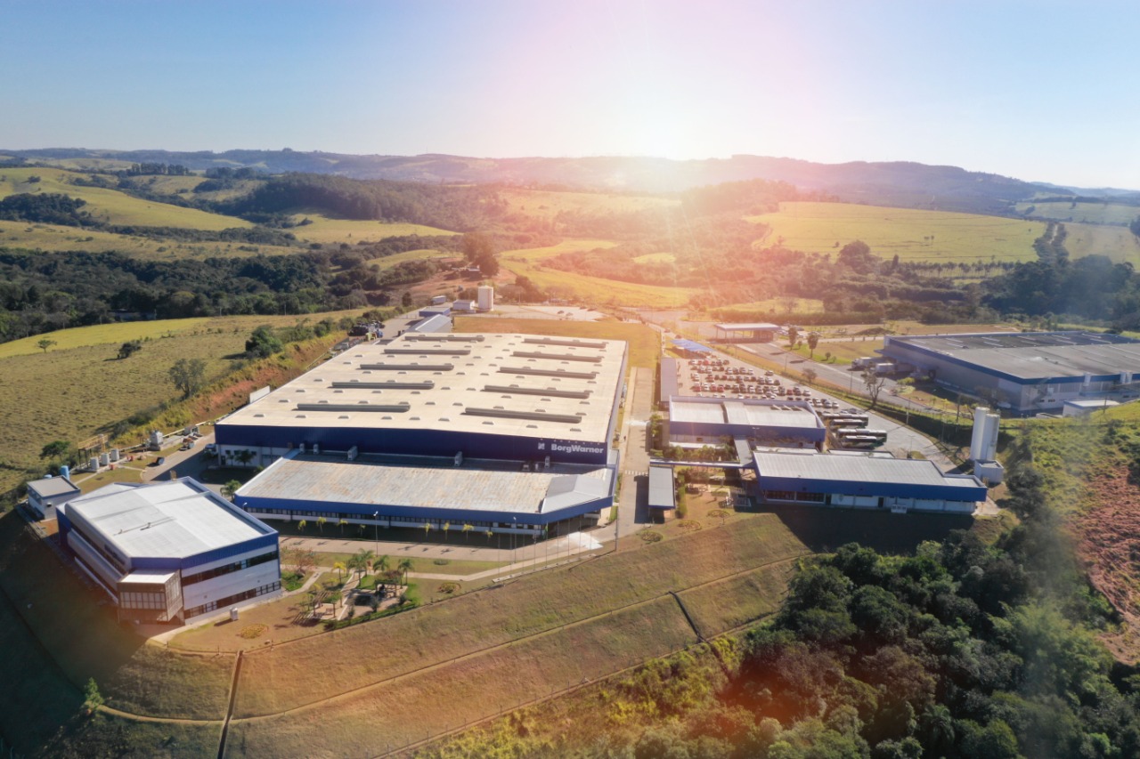 Aerial photograph of a large industrial complex situated in a rural landscape with rolling hills and greenery.