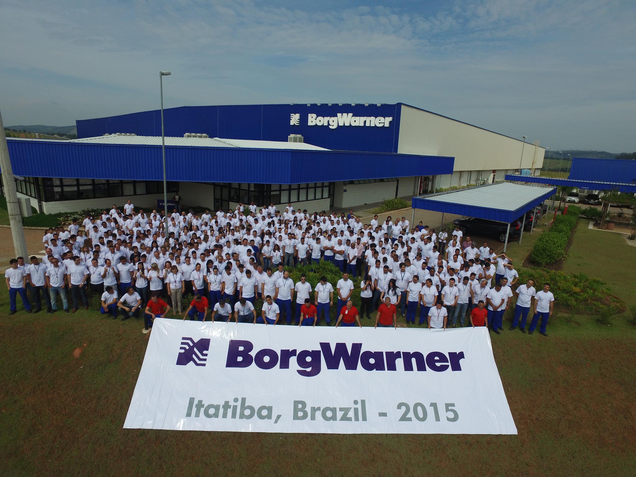 Employees with banner in front of facility