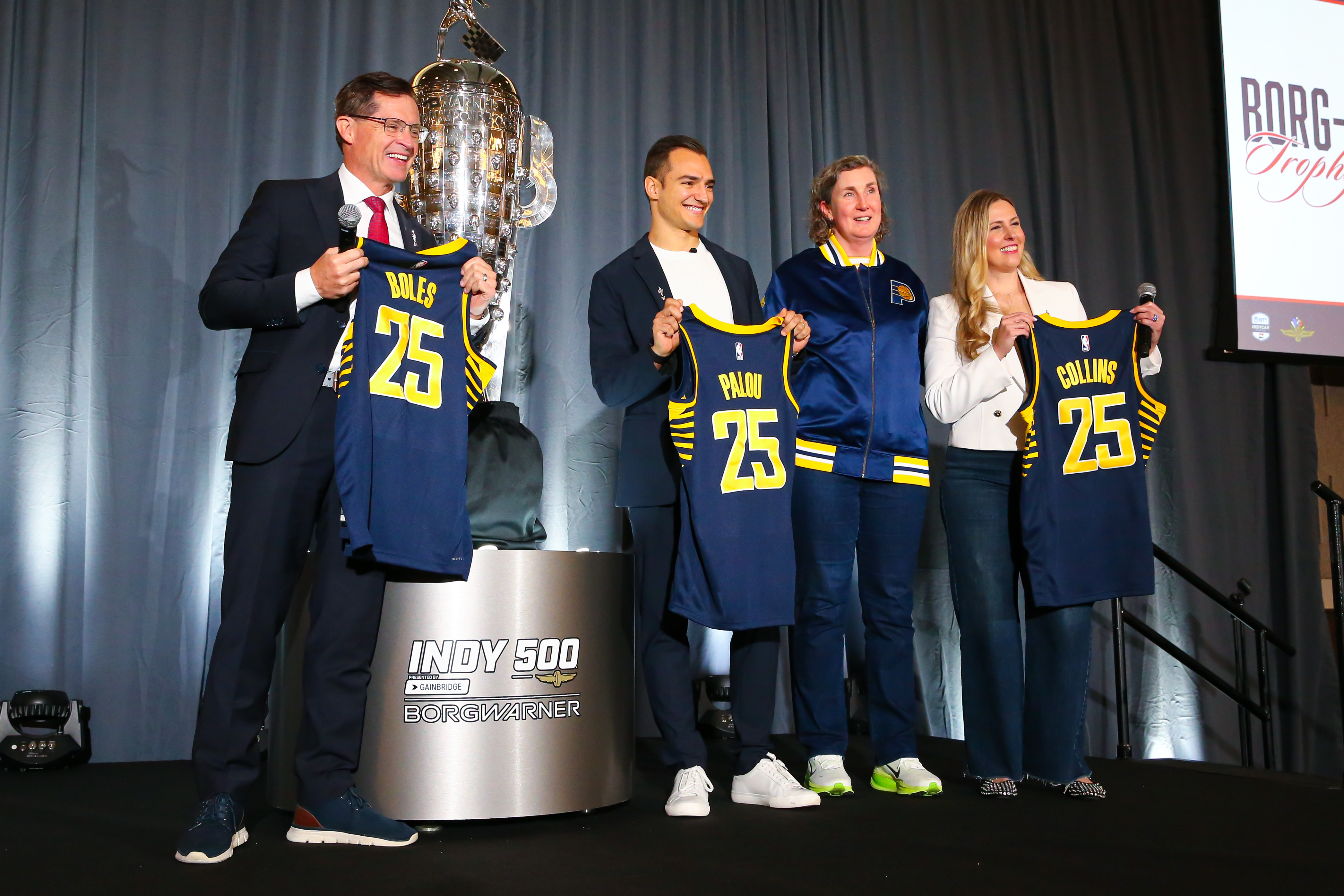 Four people onstage with a trophy and personalized basketball jerseys