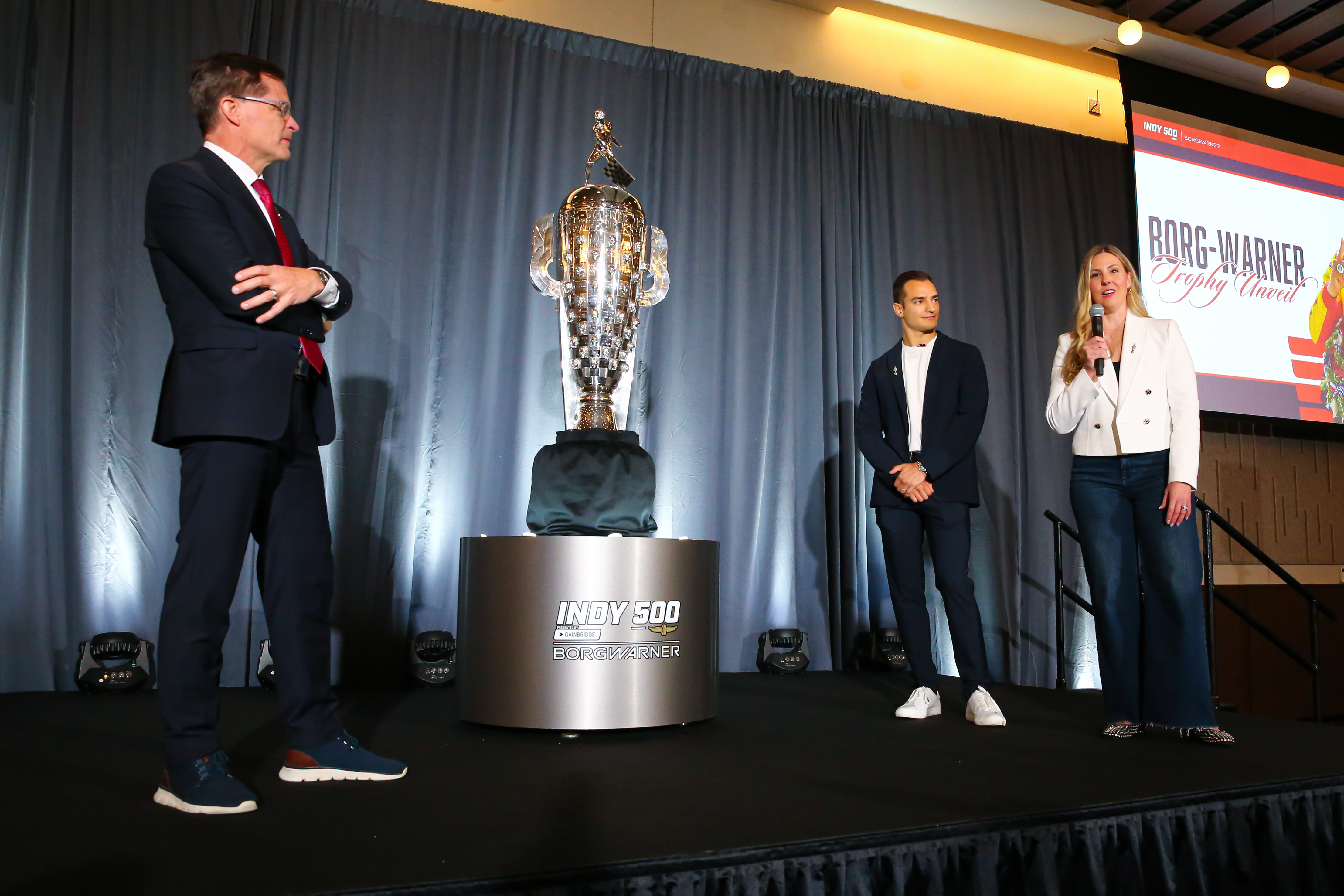Three people and a silver trophy onstage