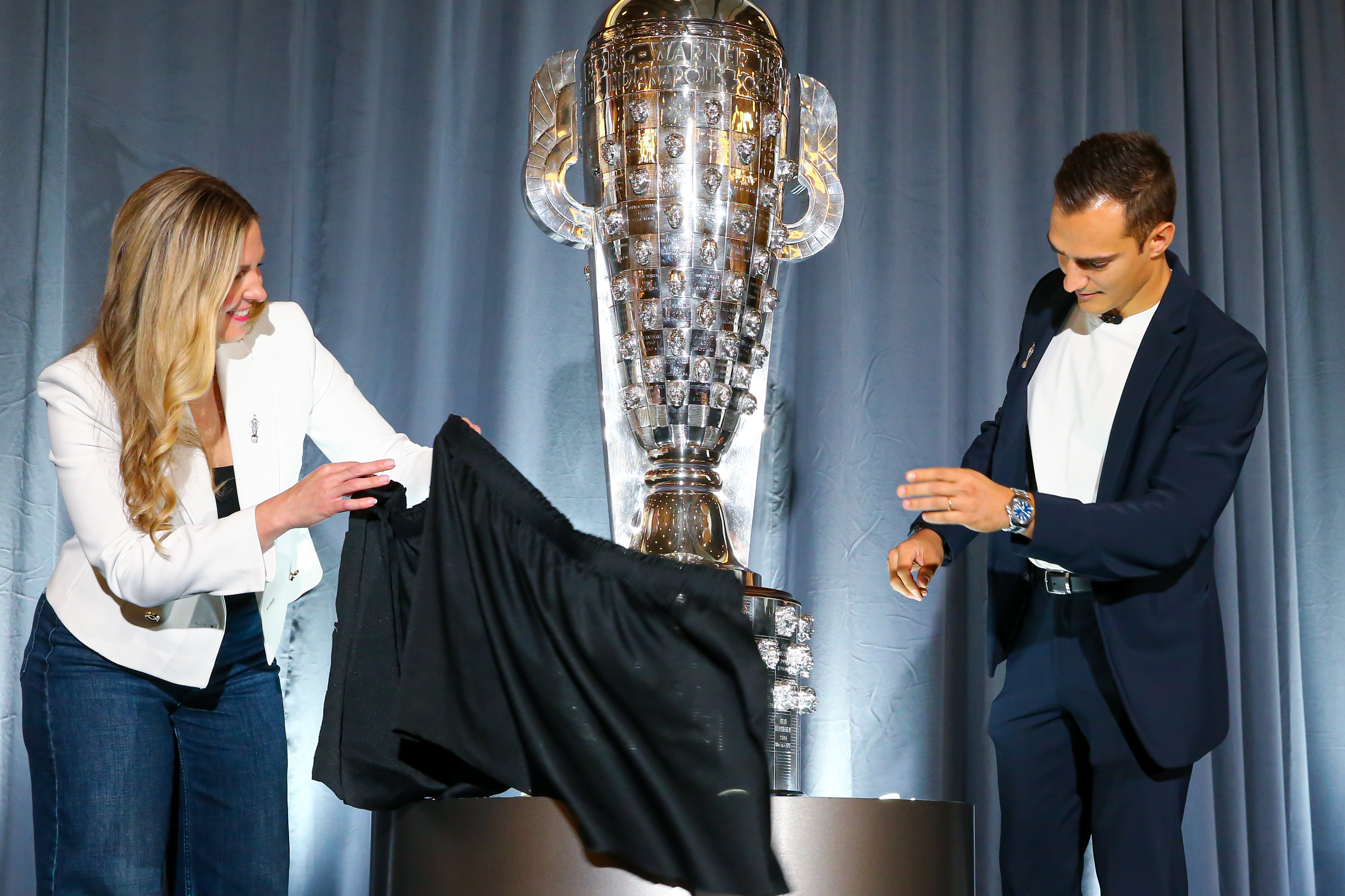 Two people look at silver trophy onstage