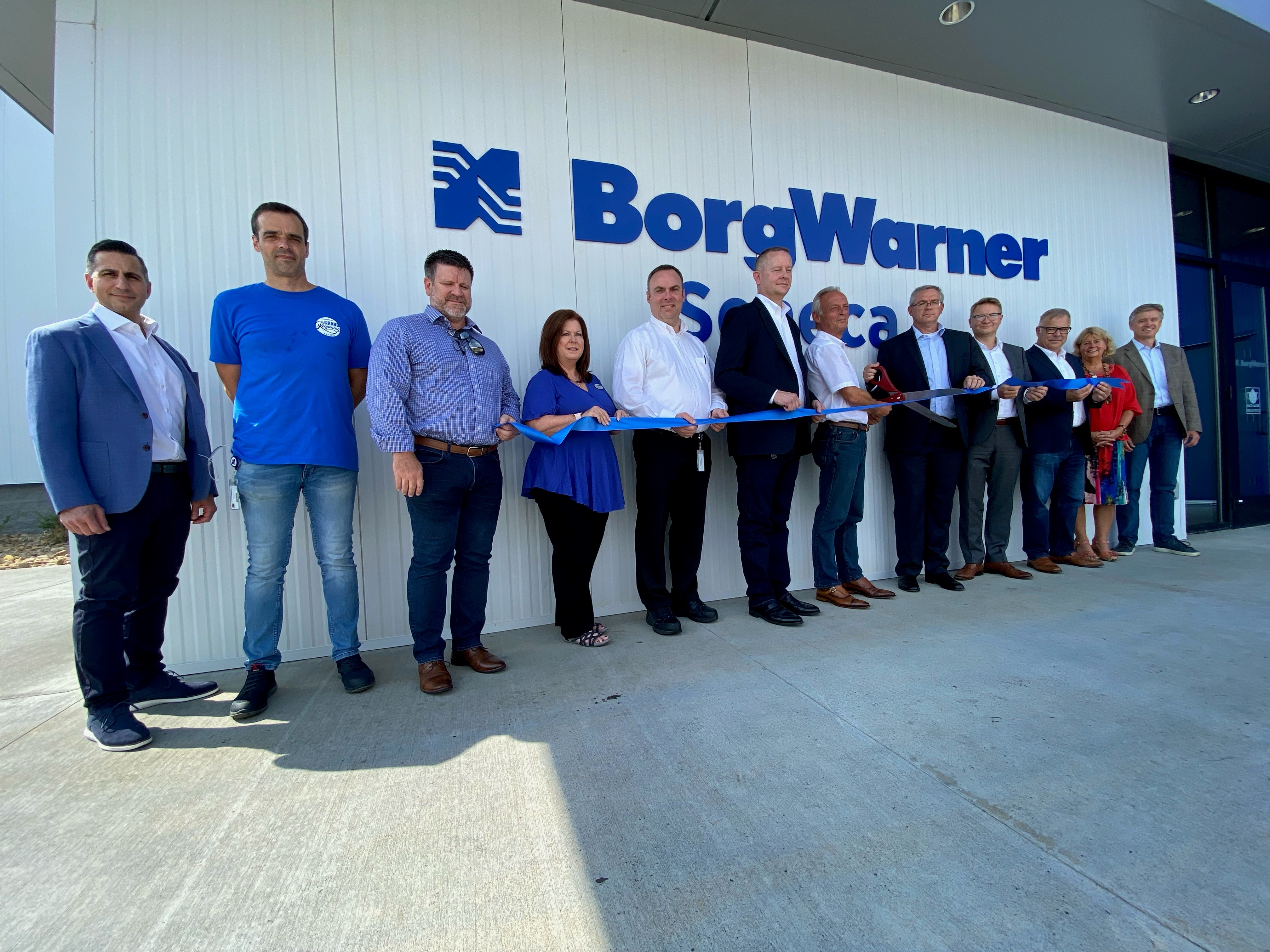 Group of twelve people holding blue ribbon stand in line smiling