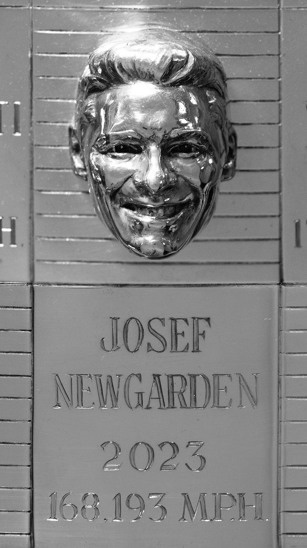 Close up of silver trophy featuring man's 3-D face and name, year and speed