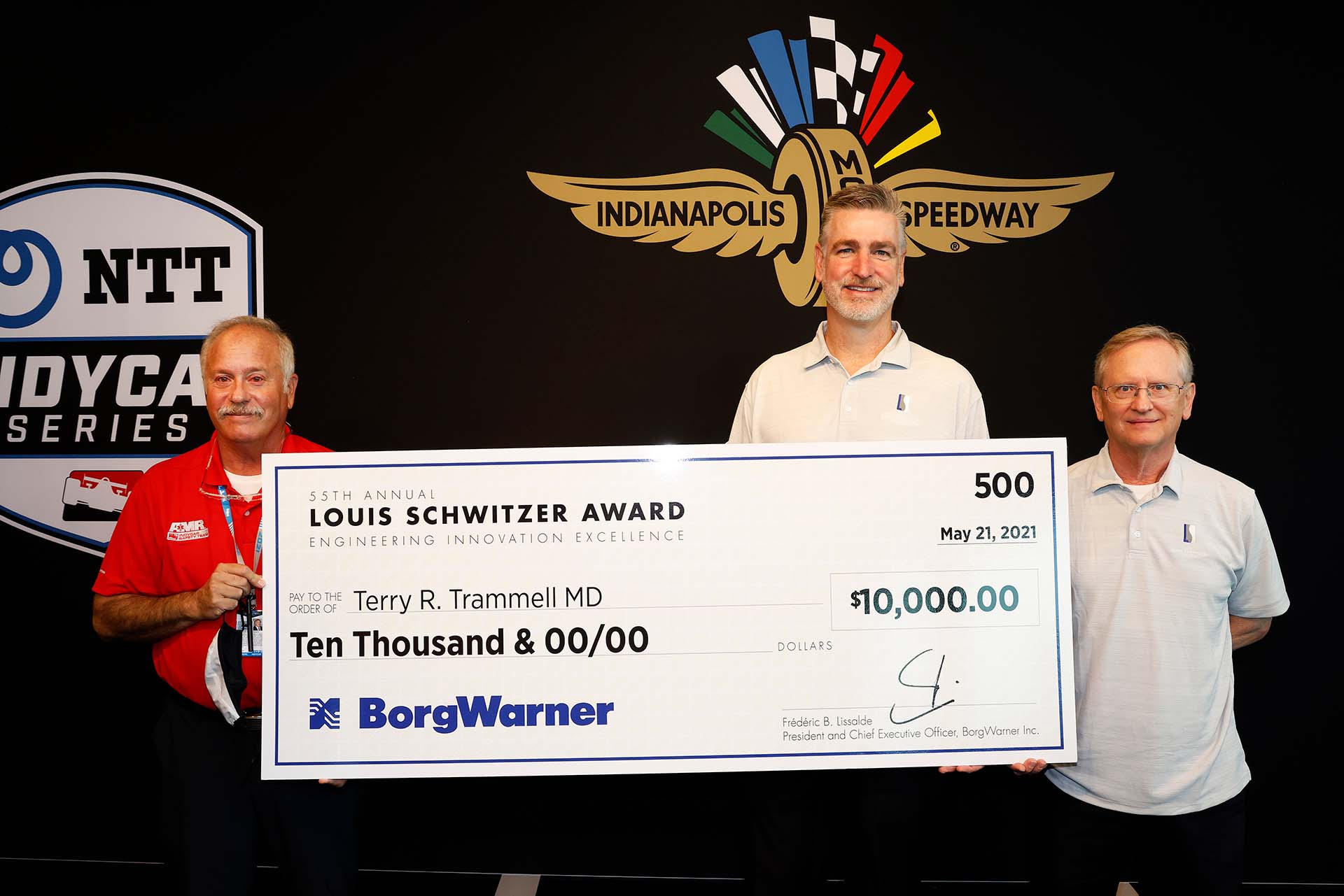 Three men stand holding large check in front of black, logo background