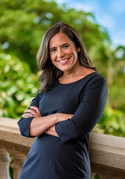 Woman in navy blue dress standing in front of bridge and greenery