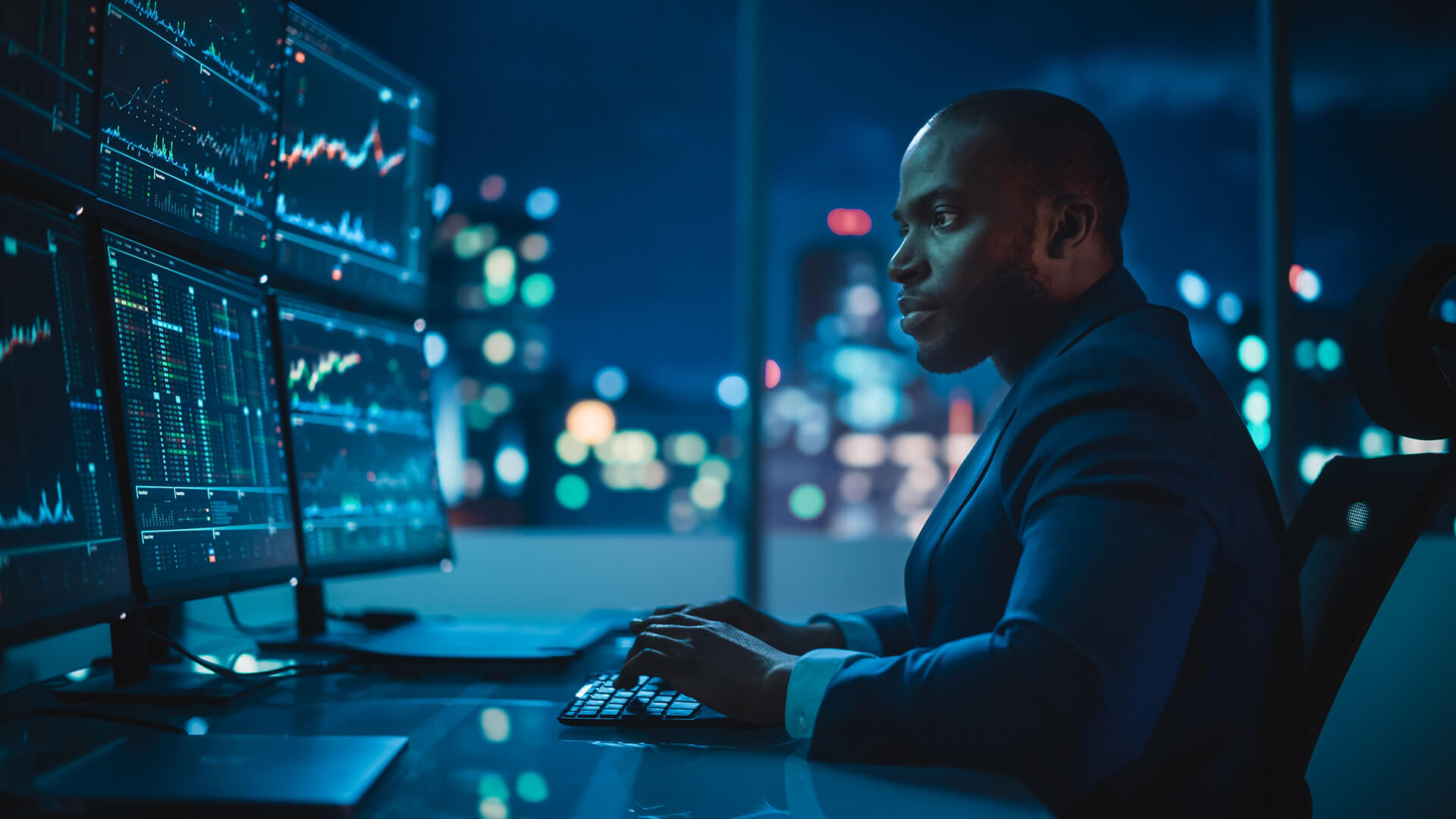 Male broker looking at monitors in office