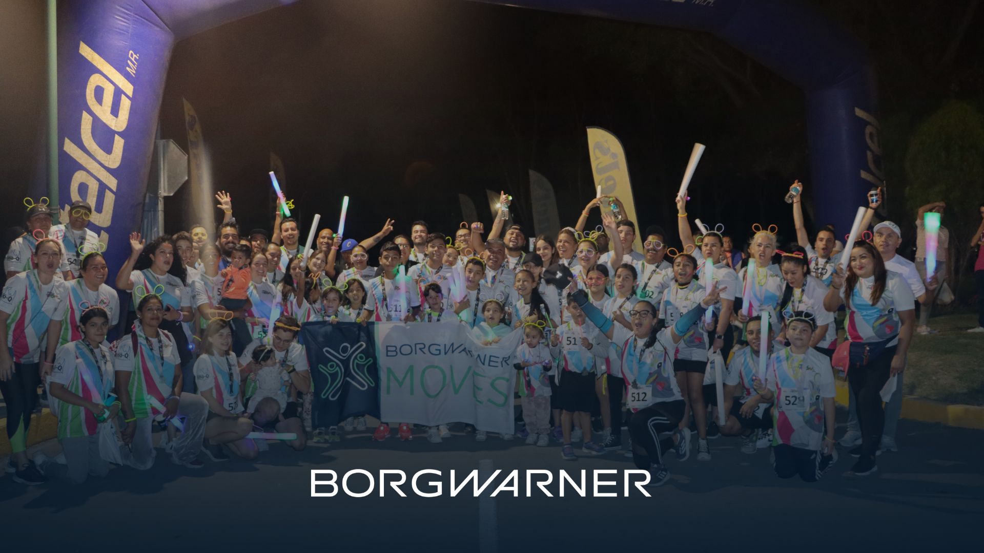 People cheering holding a BorgWarner Moves sign
