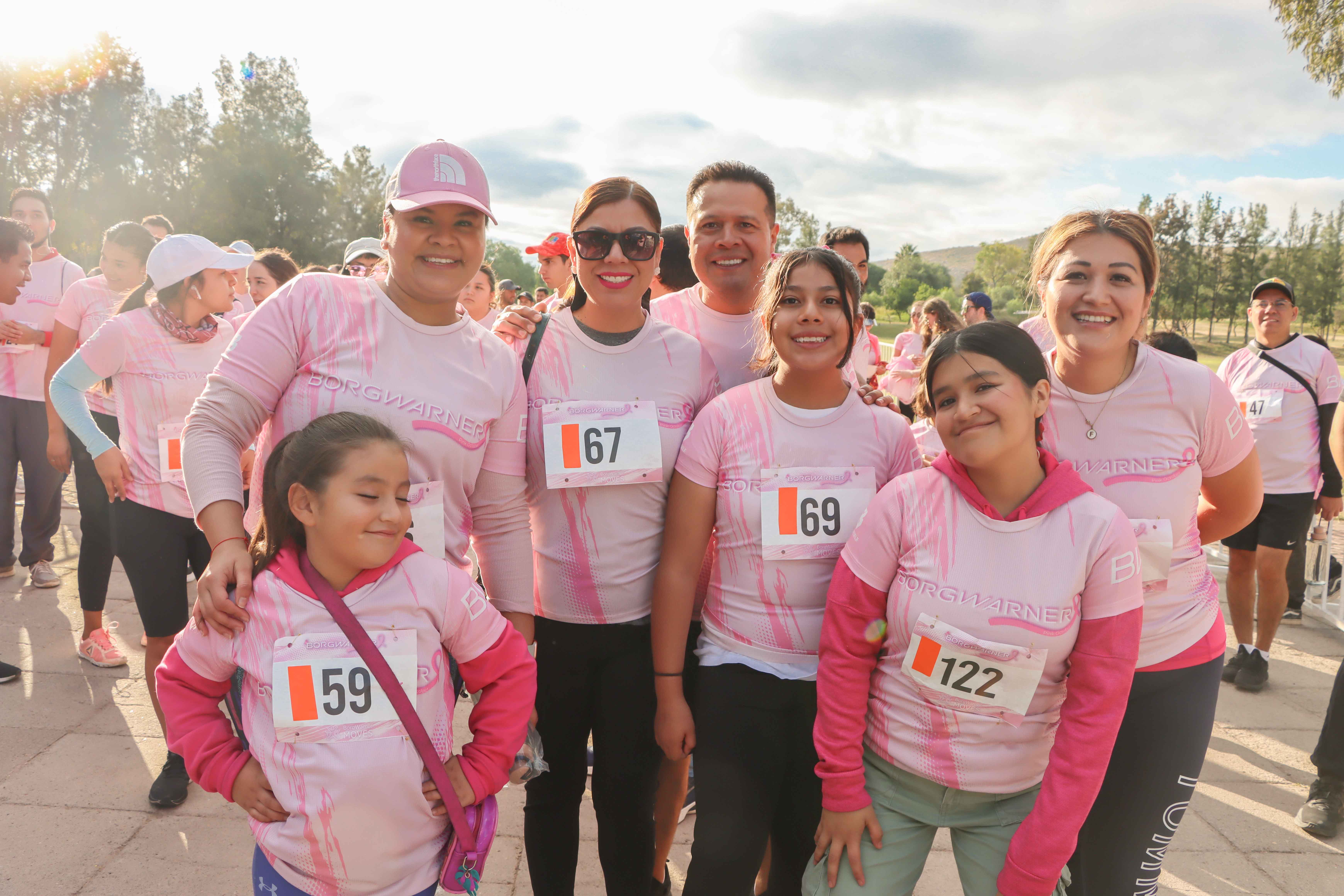 Group of people wearing race bibs and pink shirts